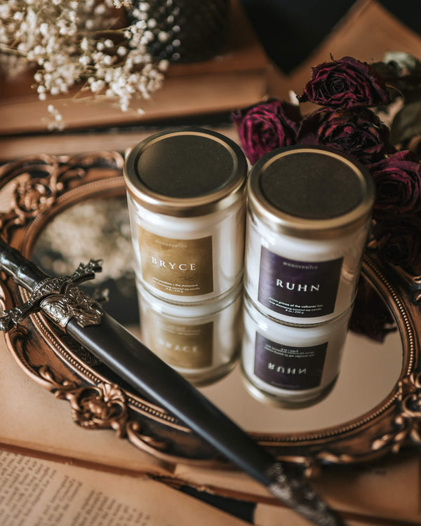 Wonderwick Bryce and Ruhn candles styled on a gilded mirror tray with dried roses and a dagger
